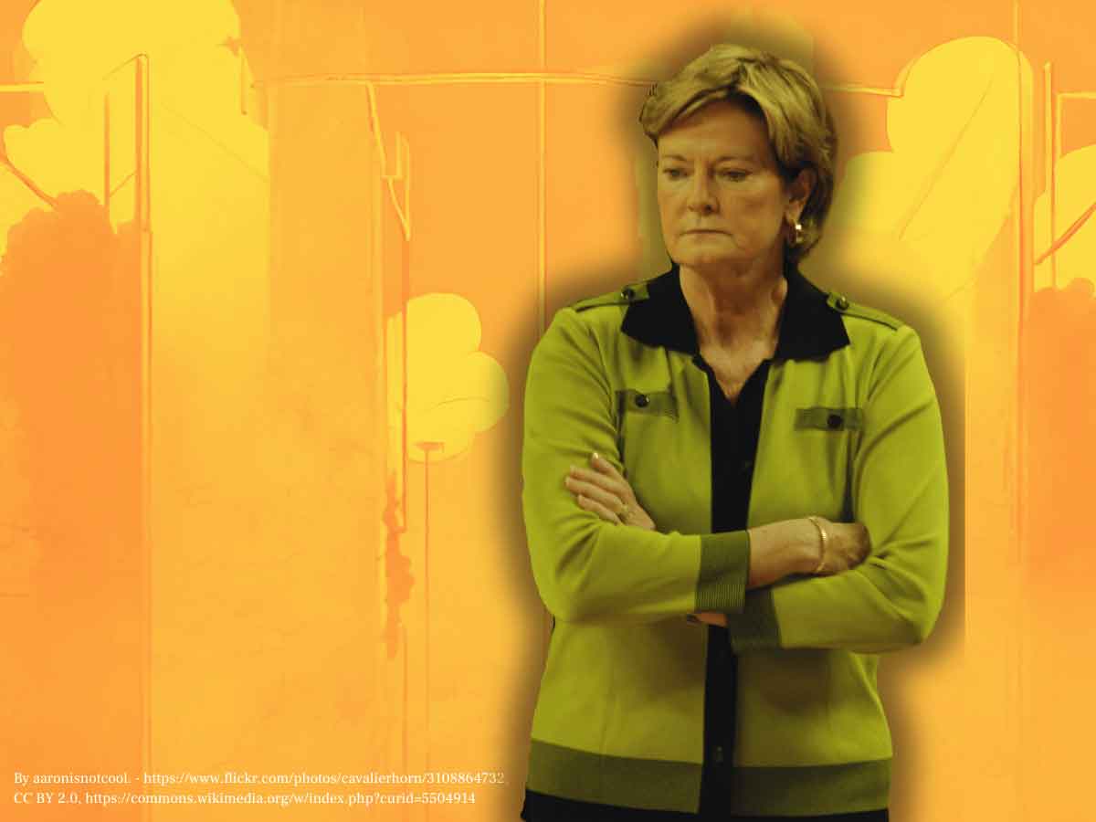 A photo of Pat Summitt with her arms crossed and looking down over an orange background.