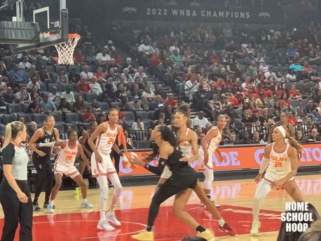 A photo of a live WNBA game between the Las Vegas Aces and the Connecticut Sun. A'ja Wilson of the Las Vegas Aces drives toward the basket.