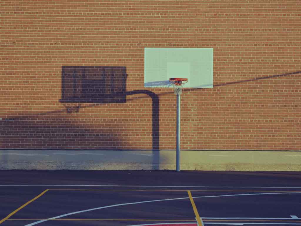 A regulation size basketball hoop at an outdoor park.